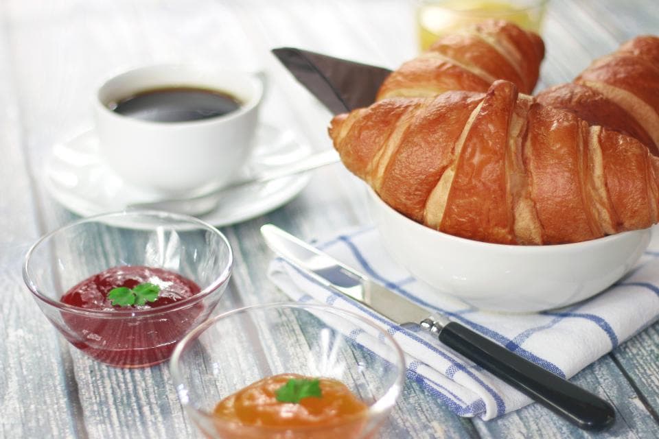 Croissants and jam beside a cup of black coffee