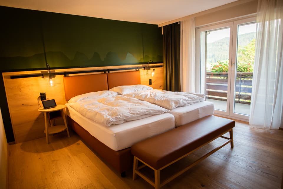A king bed with crisp white linen and the balcony doors open to the light