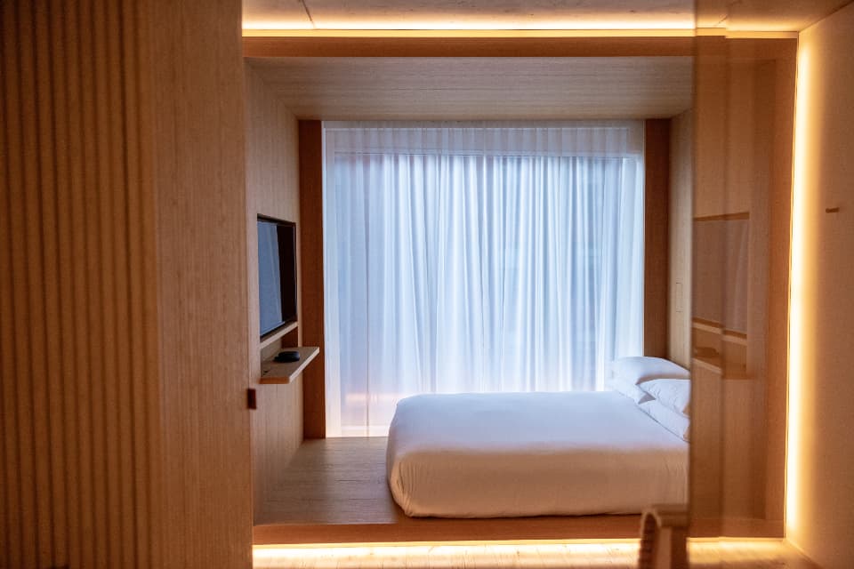A timber-panelled bedroom lit warmly, the bed set back in an alcove